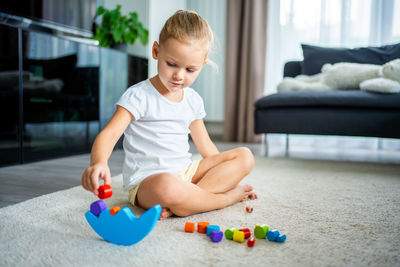 Portrait of boy playing with toy while sitting on sofa at home