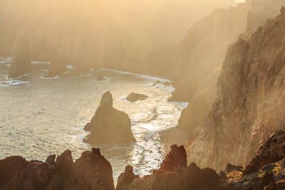 Rock formations in sea during sunset