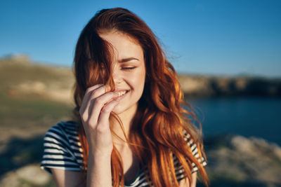 Portrait of smiling young woman against sky