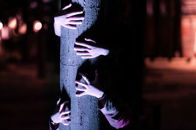 Cropped hand of women holding tree trunk outdoors