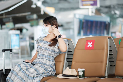 Woman wearing flu mask sitting at airport