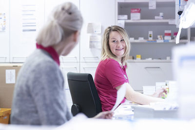 Smiling pharmacist talking with colleague at medical store