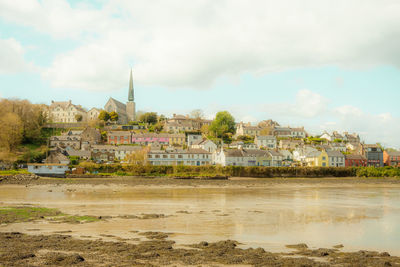 Buildings by river against sky