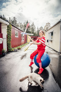 Woman with juggling pins sitting on fitness ball on road