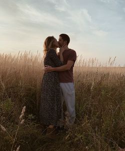 Rear view of couple standing on field against sky