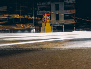 Light trails on road by buildings in city at night