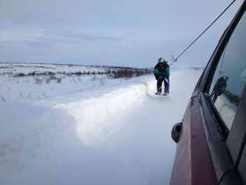 People on sea shore against sky during winter