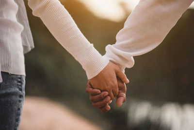 Midsection of couple holding hands