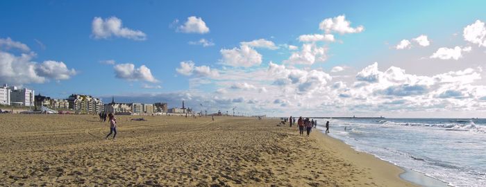 Panoramic view of people at beach against sky