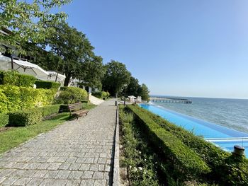 Footpath by sea against clear sky