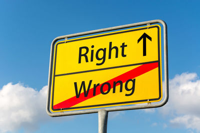 Low angle view of road sign against blue sky