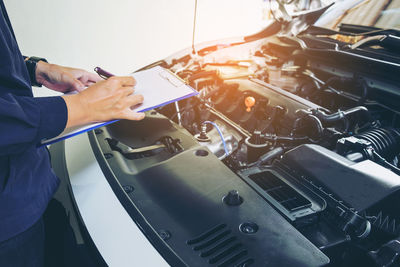 Cropped hands of mechanic repairing car in garage