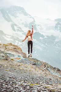 Jumping woman with backpack on mountain background. top of gornergrat, zermatt, swiss. alps hiking