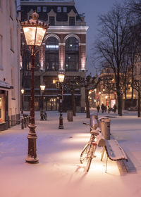 Illuminated street light and buildings in city at winter