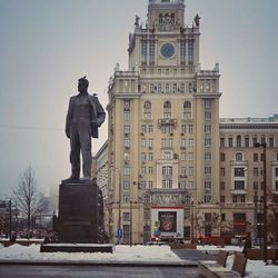 Statue in city against clear sky during winter