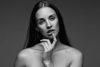 Portrait of shirtless woman with long hair against gray background