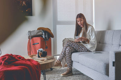 Low angle view of young woman sitting on sofa at home