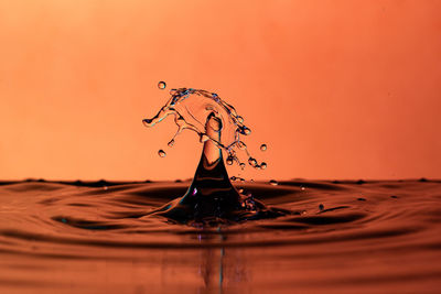 Close-up of water splashing against orange sky