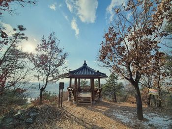 Gazebo amidst trees and building against sky