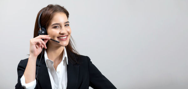 Portrait of smiling young woman using mobile phone against clear sky