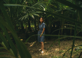 Full length portrait of woman standing by tree