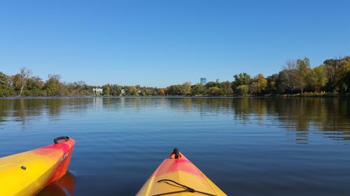 Boats moored in lake against clear blue sky