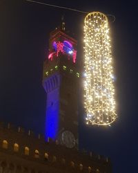 Low angle view of illuminated clock tower at night