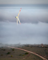 Wind turbines on field against sky