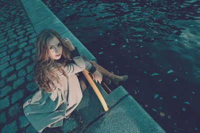 High angle portrait of woman sitting by canal