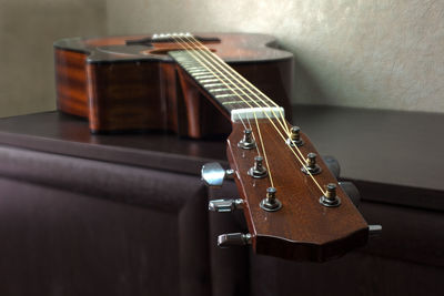 Close-up of guitar on table against wall