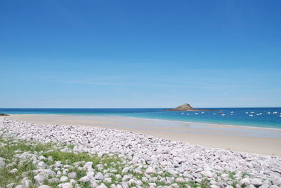 Scenic view of beach against clear blue sky