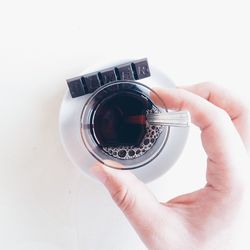 Close-up of cropped hand holding mobile phone over white background