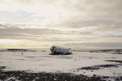 Abandoned airplane on snowy land against sky during winter