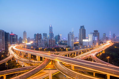 High angle view of light trails on road amidst buildings in city against sky