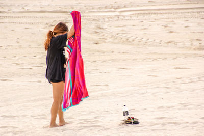 Woman holding towel while standing at beach