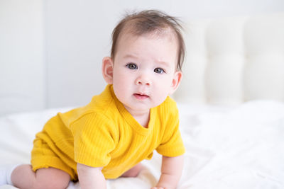 Portrait of cute baby boy lying on bed at home