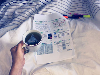 Midsection of woman holding coffee cup on bed