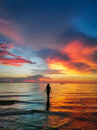 Silhouette man standing on beach against sky during sunset