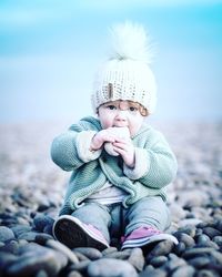 Portrait of cute baby girl on beach against sky