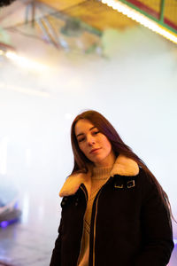 Portrait of young woman looking away while standing in winter