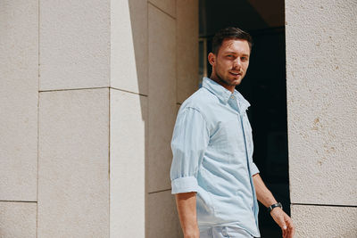 Portrait of young man standing against wall