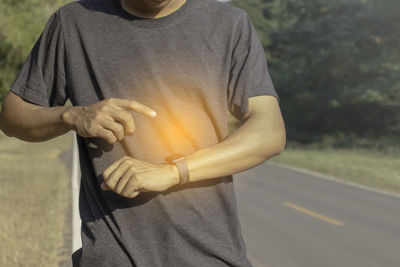 Midsection of man holding umbrella standing on road