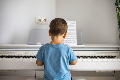 Rear view of boy playing piano