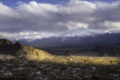 Aerial view of townscape and mountains against sky