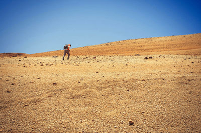 Low angle view of man climbing hill against clear sky