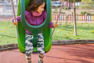 Girl sitting on swing at park