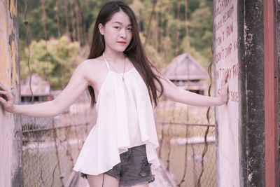 Portrait of beautiful young woman standing on footbridge