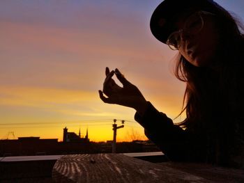 Portrait of silhouette woman using smart phone against sky during sunset