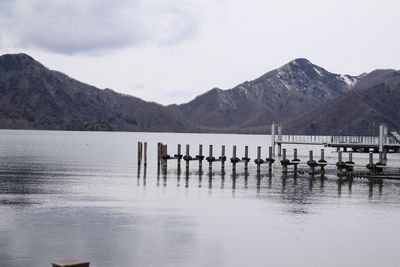 Wooden posts in lake against mountains