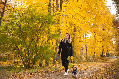 Full length of woman walking with dog in forest